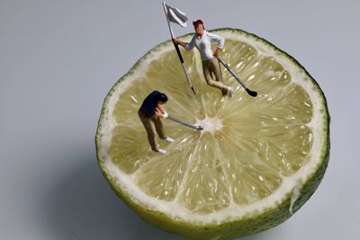 Close-up of man with lemon slice against white background