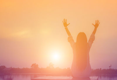 Rear view of silhouette person standing in front of sunset