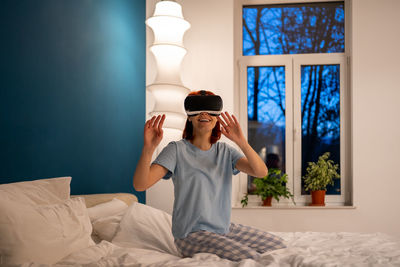 Portrait of young woman sitting on bed at home