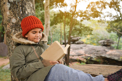 Boy reading book while sitting on bench