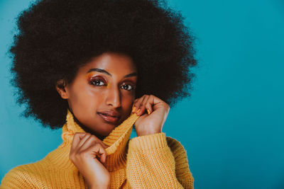 Close-up portrait of a young woman over blue background