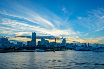 City at waterfront against cloudy sky