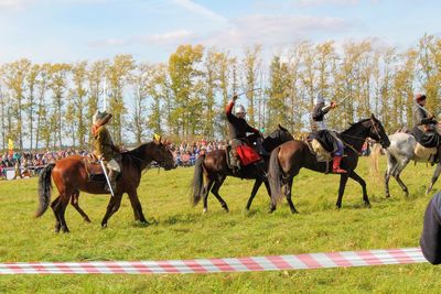 Horses running on field against sky