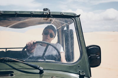 Portrait of young man driving car on desert