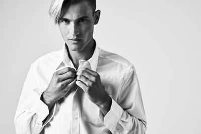 Portrait of young man standing against white background