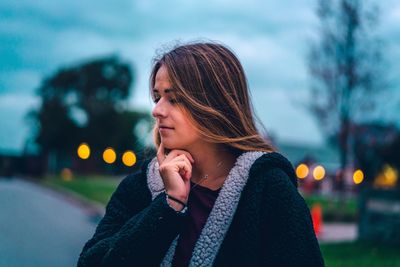 Portrait of woman looking away while standing in snow