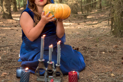 Midsection of woman holding pumpkin on field