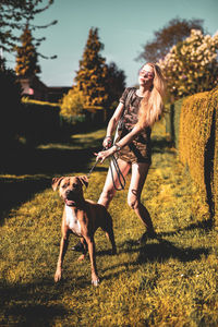 Young woman with dog walking on field