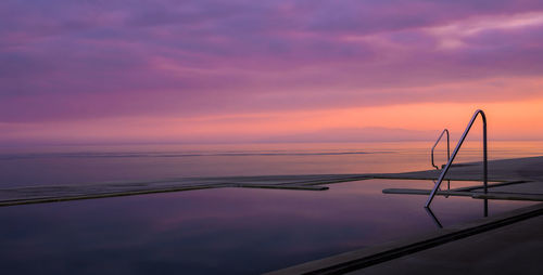 Scenic view of infinity pool against sky during sunset