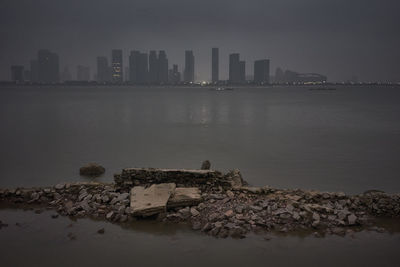 Cityscape by sea against sky