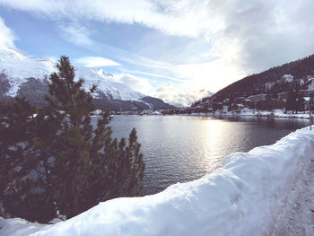 Scenic view of lake by snowcapped mountains against sky