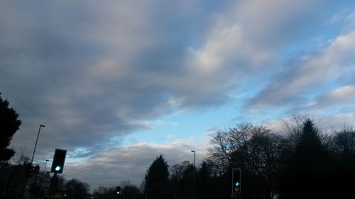 Low angle view of silhouette trees against cloudy sky