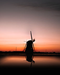 Silhouette of cranes against sky during sunset