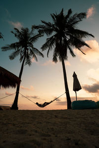 Low angle view silhouette of palm tree at beach against sky during sunset