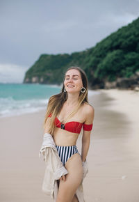 Portrait of a smiling young woman standing on beach