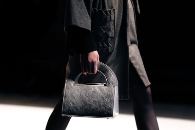 Fashion details of grey coat and small leather handbag in a woman's hand. elegant clothing