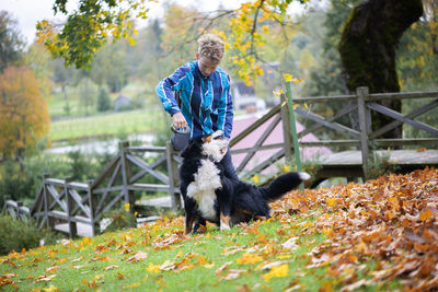 Outdoor portrait of boy with bernese mountain dog in autmn park. friendship of teenager with pet.
