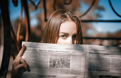 Portrait of young woman holding paper outdoors