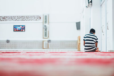 Rear view of man praying in mosque