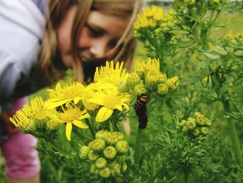 Curious girl looking at caterpillar on flower