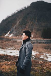 Young man standing on field against sky