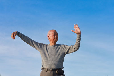 Low angle view of man standing against blue sky