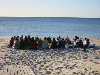 Group of people on beach against clear sky