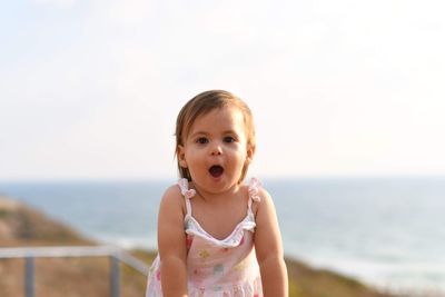 Portrait of cute girl standing against sky