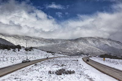 Snow covered road by mountain against sky