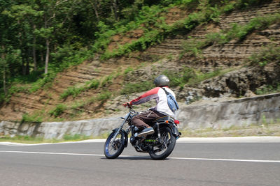 Rear view of man riding motorcycle on road