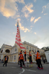 People on building against cloudy sky