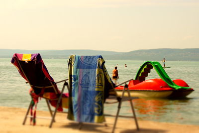 Deck chairs on beach against sky