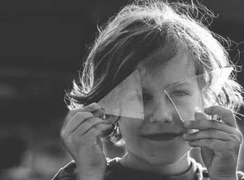 Portrait of boy holding broken glass over eyes