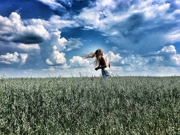 Woman on field against cloudy sky