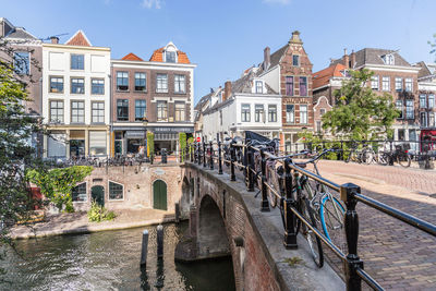 Bridge over canal amidst buildings in city against sky