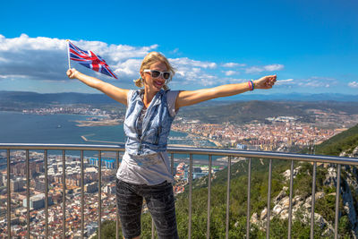 Young woman standing on railing against cityscape