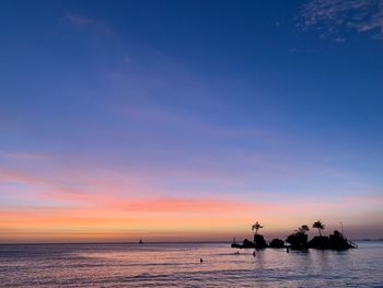 Silhouette boats in sea against sky during sunset