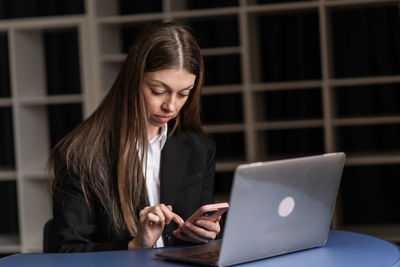 Businesswoman using digital tablet while sitting on table