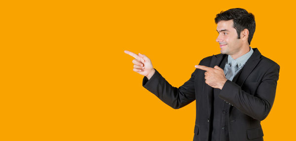 Man holding camera while standing against yellow background