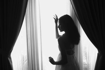 Woman looking through window at home