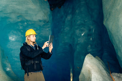 Reflection of man photographing on rock