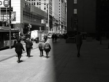 People walking on street amidst buildings in city