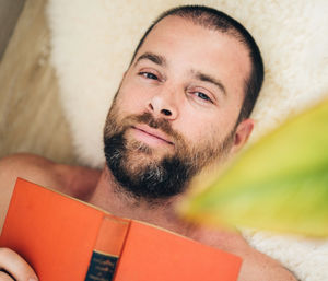 Portrait of man lying down reading a book