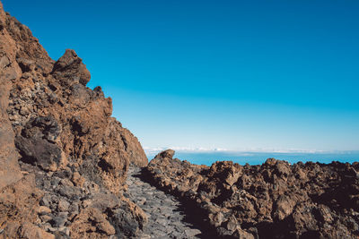 Rock formations in sea against clear blue sky