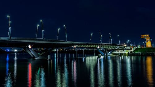 Illuminated bridge over sea against sky