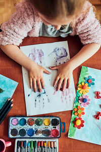 Little girl preschooler painting a picture using colorful paints and crayons