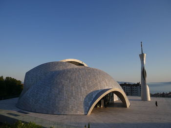 Built structure by sea against clear blue sky