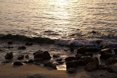 Scenic view of rocks at beach during sunset