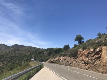 Road by mountain against blue sky