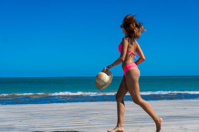 Full length of woman on beach against clear blue sky